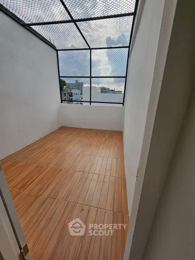 Spacious enclosed balcony with wooden flooring and city view