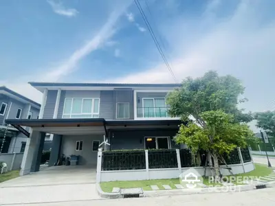 Modern two-story house with spacious driveway and lush greenery