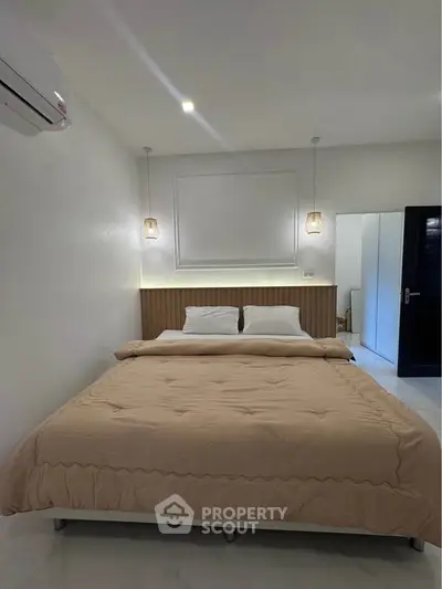 Spacious modern bedroom with elegant lighting and cozy bedding in a stylish apartment.