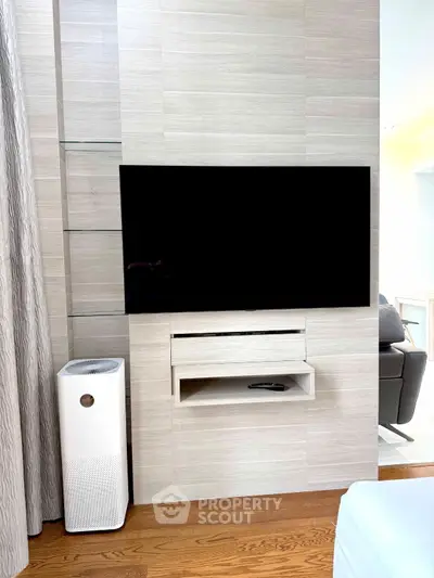 Modern living room with sleek TV setup and air purifier on wooden floor