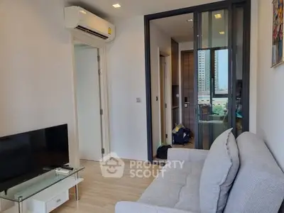 Modern living room with air conditioning and glass door, featuring a cozy sofa and sleek TV setup.