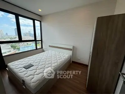 Modern bedroom with large window offering stunning city view and cozy wooden flooring.