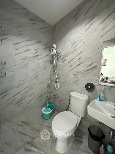 Modern bathroom with sleek tiles and essential fixtures in a contemporary home.