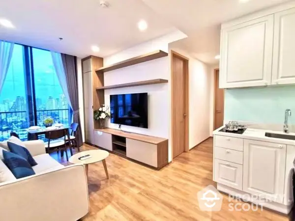 Bright and modern open-layout living room with sleek white kitchen, large windows offering city views, and warm wooden flooring.