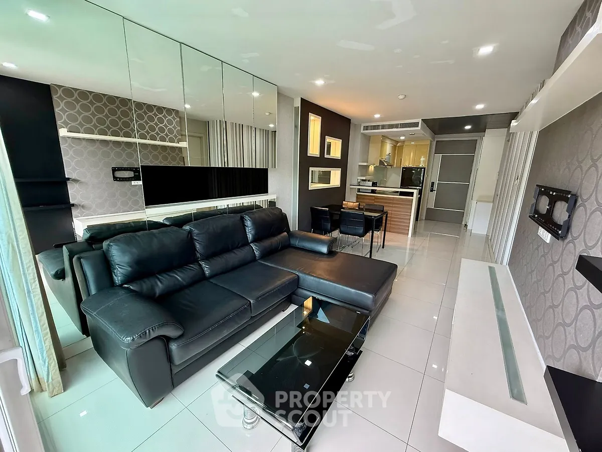 Modern living room with sleek black leather sofa and open kitchen layout