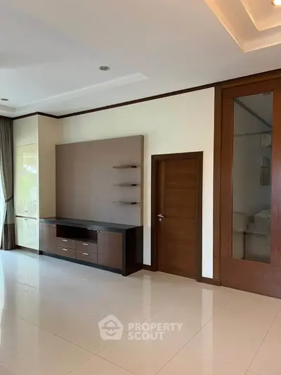 Spacious modern living room with sleek wooden cabinetry and large mirror, perfect for stylish living.