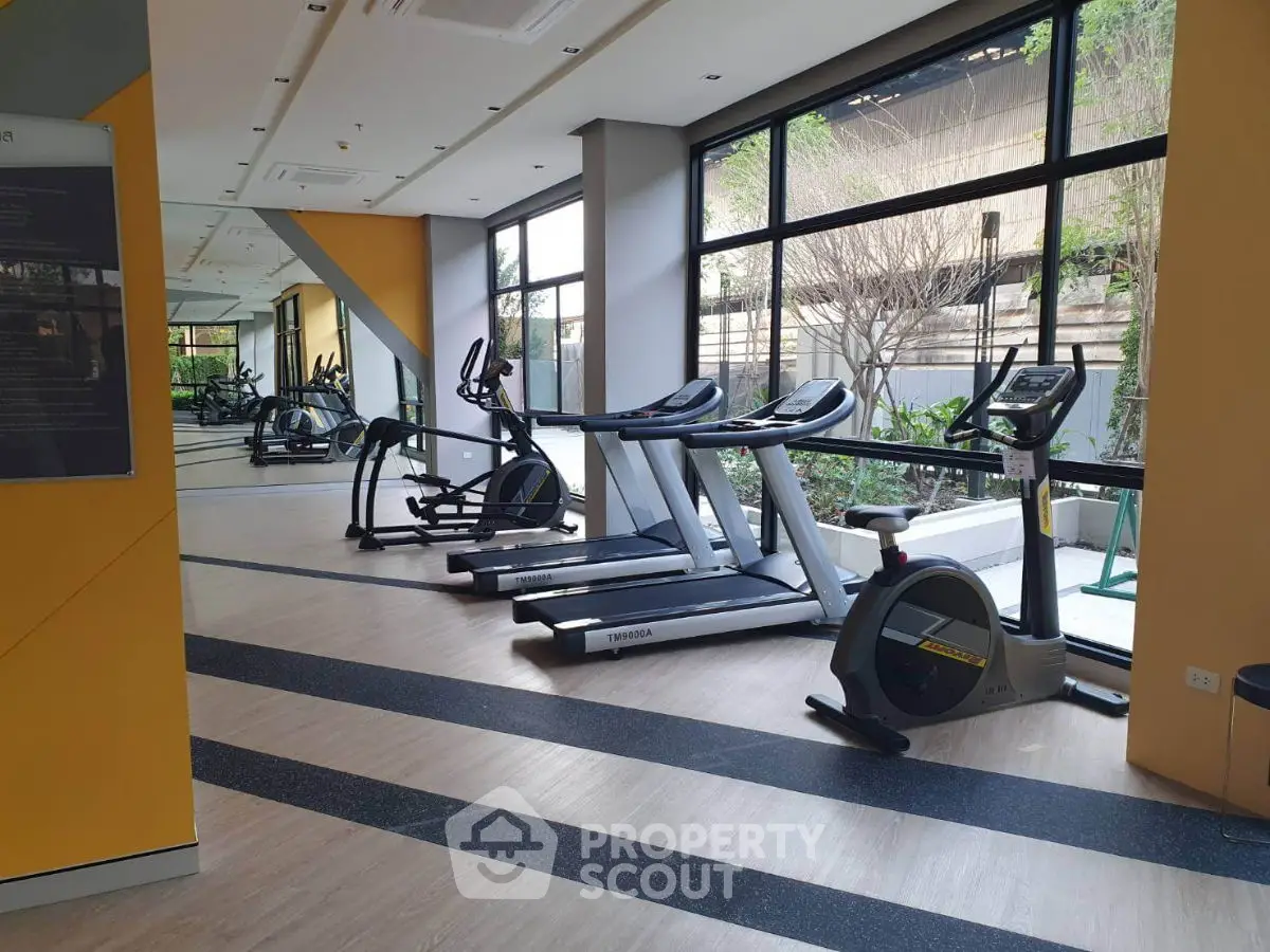 Modern gym with large windows and exercise equipment in a residential building.