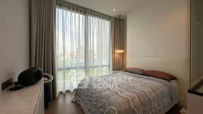 Modern bedroom with large window and city view, featuring stylish decor and cozy ambiance.