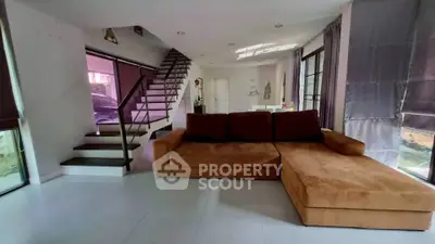 Spacious living room with modern staircase and large brown sofa