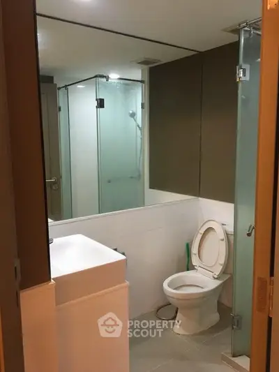Modern bathroom with glass shower and sleek fixtures in contemporary apartment.
