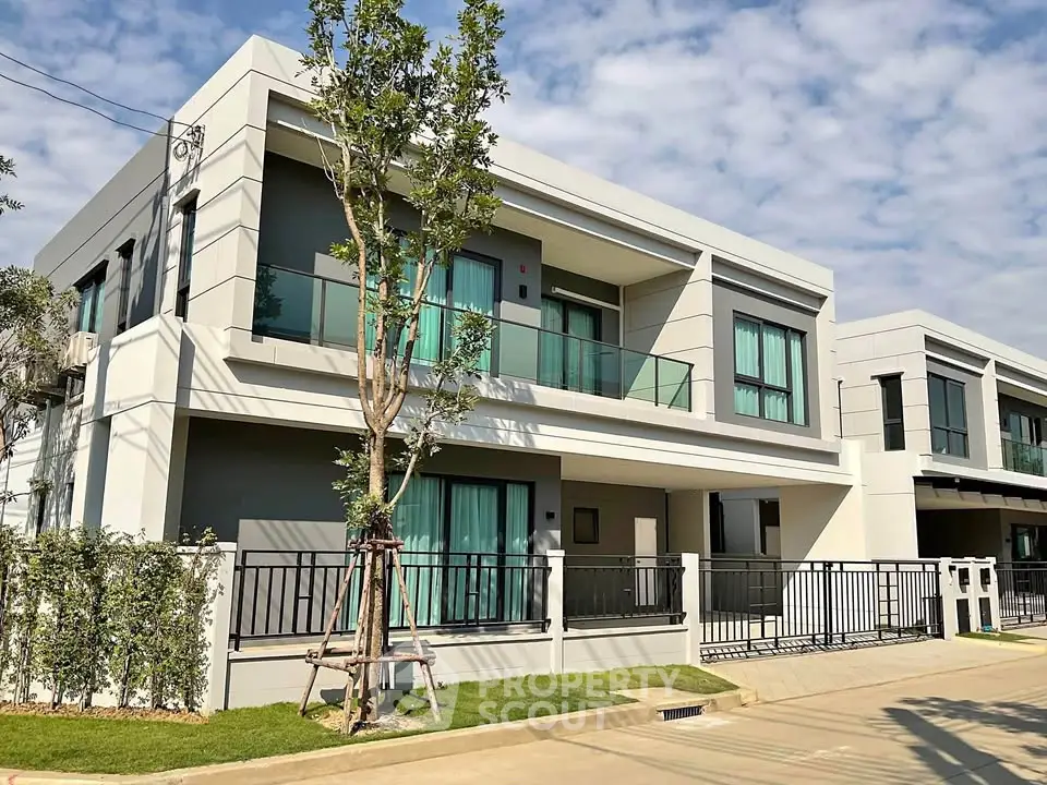 Modern two-story house with sleek design and large windows in a suburban neighborhood.