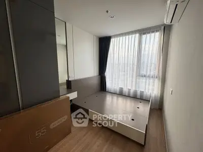 Modern bedroom with large window and built-in storage, featuring sleek design and natural light.