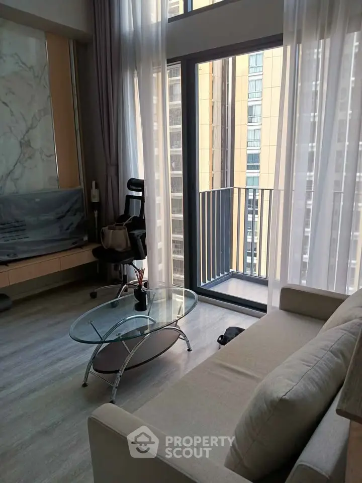 Modern living room with floor-to-ceiling windows and small balcony in urban apartment