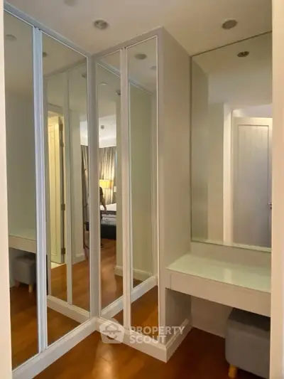 Elegant bedroom corner with mirrored closet and vanity in modern apartment