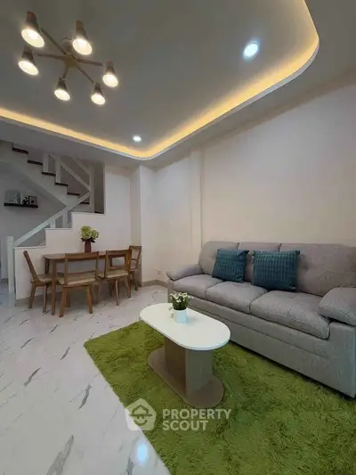 Modern living room with stylish lighting, cozy sofa, and elegant dining area in open layout.