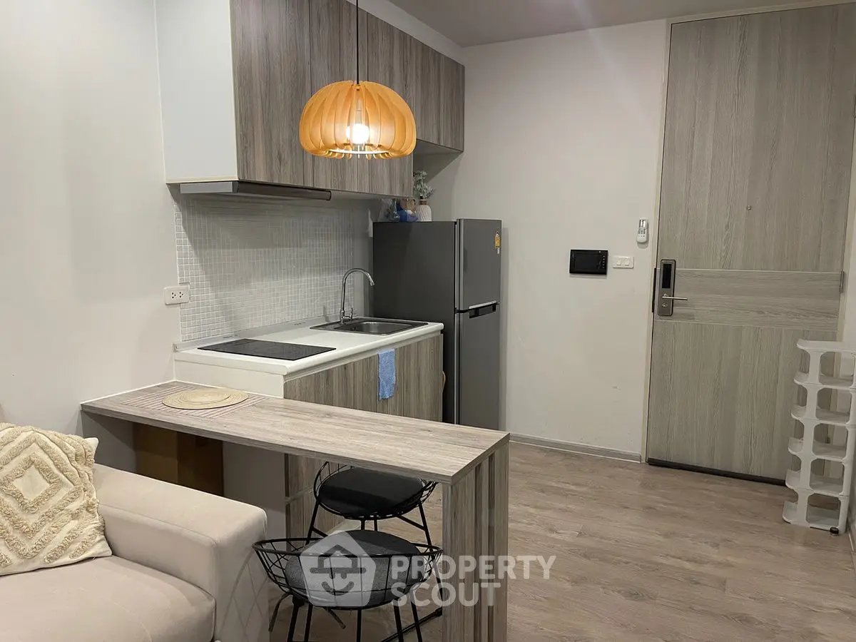 Cozy modern kitchen with sleek design and compact layout, featuring stylish lighting and contemporary appliances.
