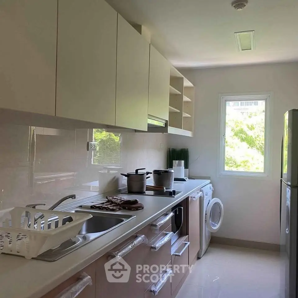 Modern kitchen with sleek cabinets, washing machine, and ample natural light.