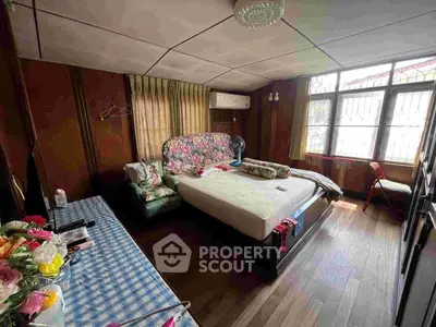 Cozy bedroom with wooden walls and large window, featuring a comfortable bed and air conditioning.