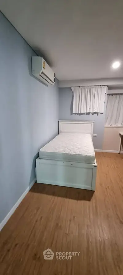 Cozy bedroom with wooden flooring and air conditioning in modern apartment.