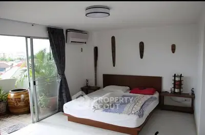 Spacious bedroom with balcony access and modern decor in a bright apartment.