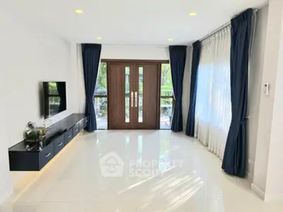 Spacious living room with modern decor, large windows, and elegant curtains.