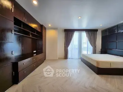 Spacious bedroom with elegant built-in storage and large window for natural light.