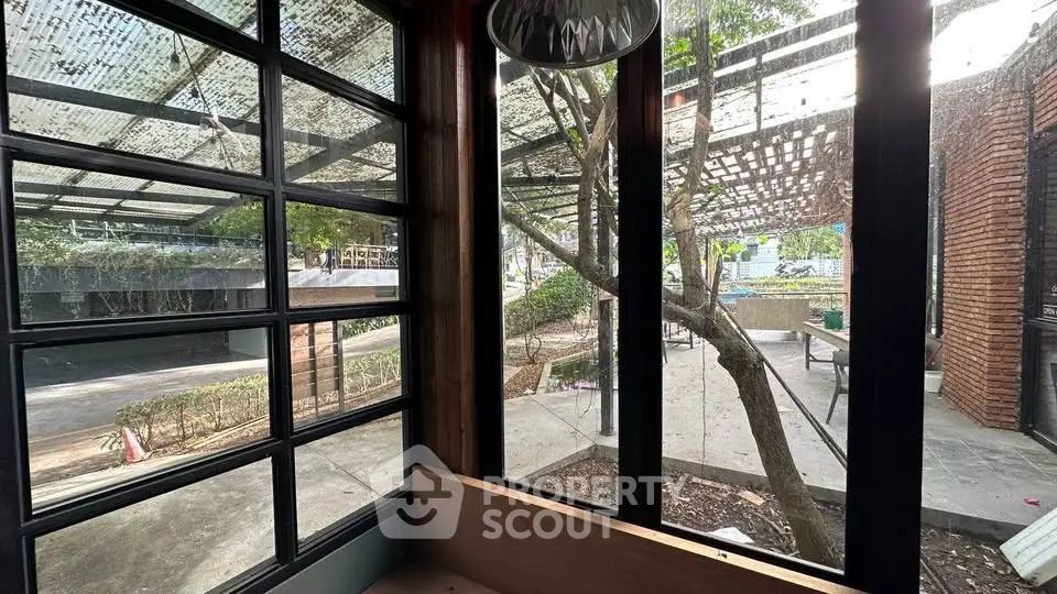 Modern industrial-style window view with outdoor seating and greenery