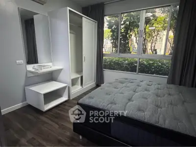 Modern bedroom with large window and stylish furniture in a serene setting.