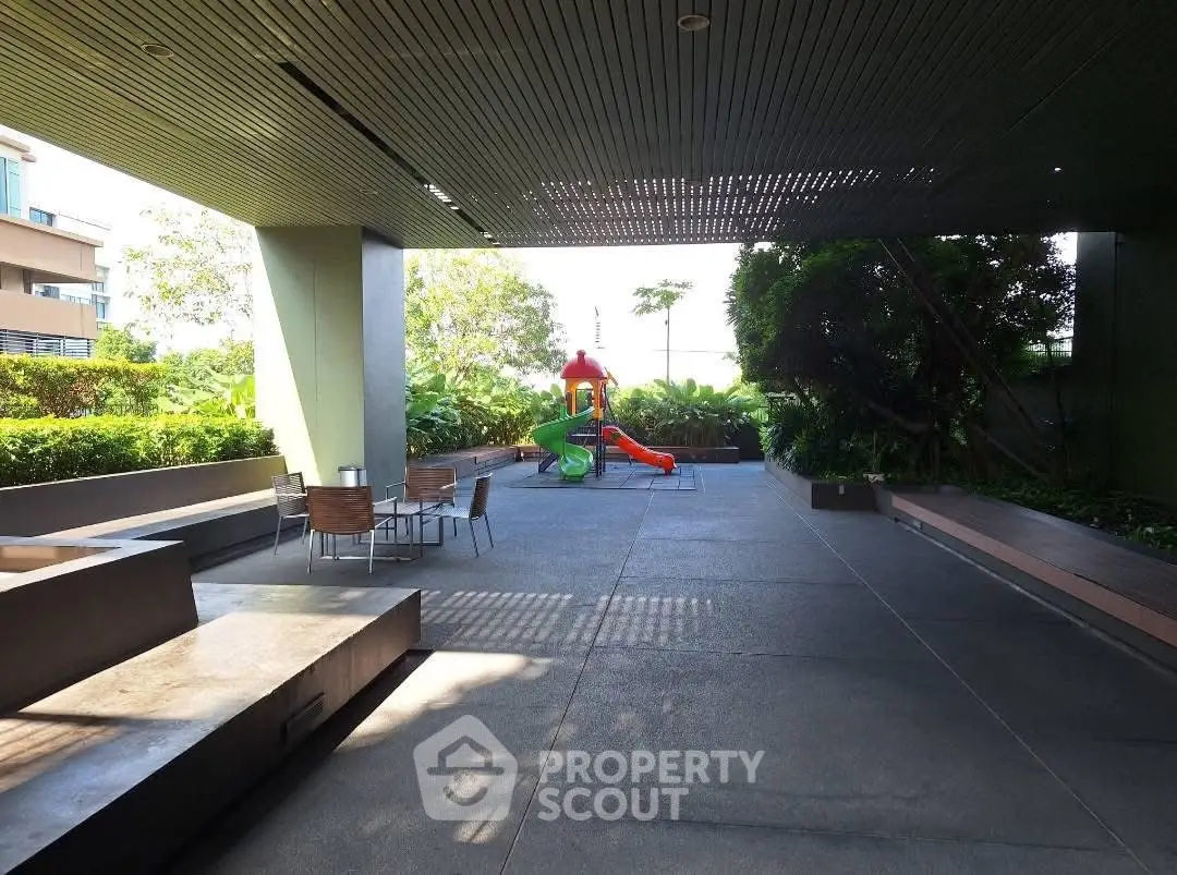 Spacious outdoor common area with playground and seating in modern residential complex.