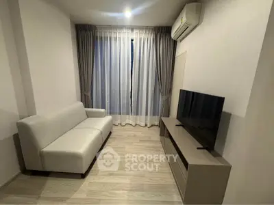 Modern living room with sleek sofa, TV, and air conditioning, featuring elegant curtains and wooden flooring.