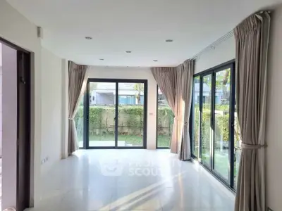 Spacious living room with large windows and garden view, perfect for natural light lovers.