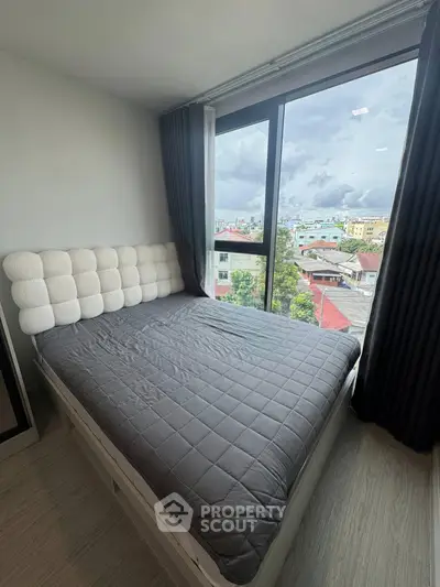 Cozy bedroom with large window offering stunning city views, featuring a modern bed and elegant curtains.