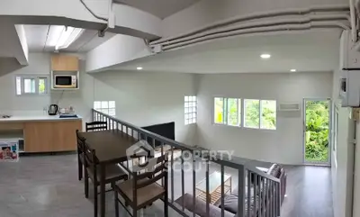 Modern loft-style living room with open kitchen and lush green view