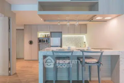 Modern kitchen with breakfast bar and stylish lighting in open layout apartment.