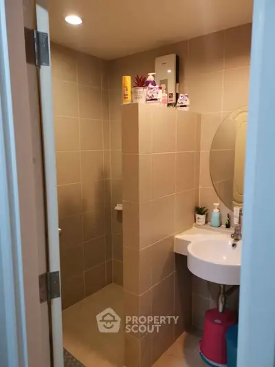 Modern bathroom with tiled walls and round mirror, featuring a compact design.