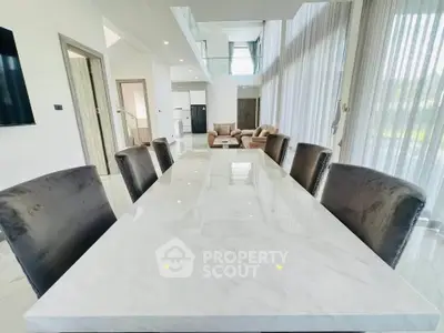 Luxurious modern dining room with marble table and plush chairs in open-plan living space.
