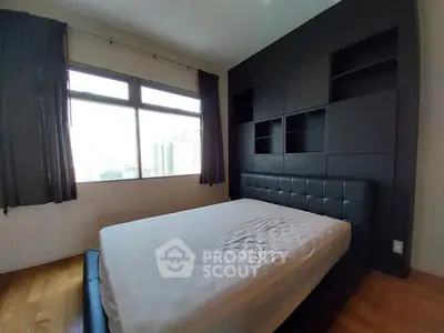 Spacious bedroom with large window offering city views and modern black furnishings.