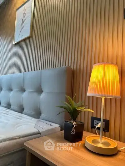 Modern bedroom with stylish headboard, wooden panel wall, and cozy bedside lamp.