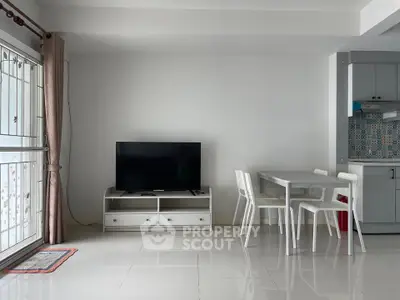 Modern living room with sleek TV setup and dining area in open layout apartment.