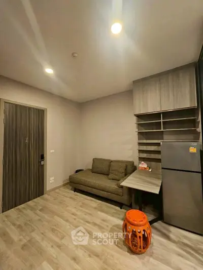Modern living room with cozy sofa and sleek fridge in a compact space