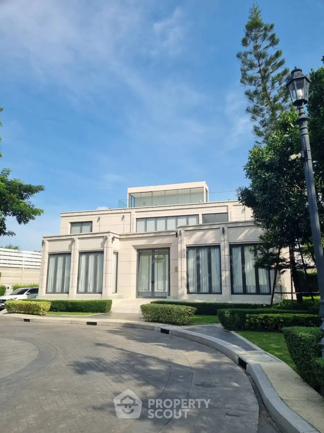 Luxurious modern mansion with elegant facade and lush landscaping under a clear blue sky.