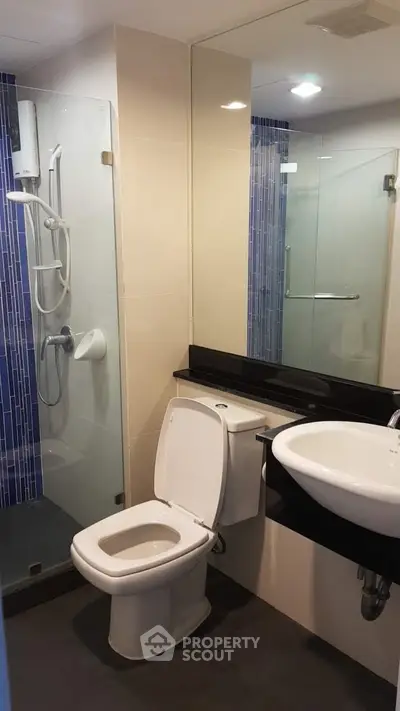 Modern bathroom with glass shower and sleek fixtures in contemporary apartment.