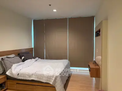 Cozy bedroom with modern decor and large window blinds, perfect for relaxation.