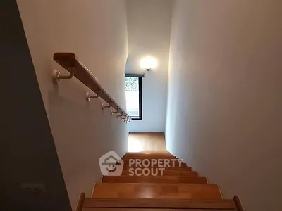 Modern staircase with wooden steps and sleek handrail in a contemporary home.