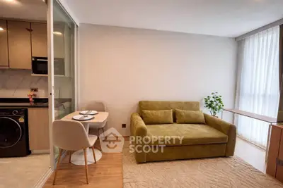 Modern living room with cozy green sofa, dining area, and open kitchen layout.