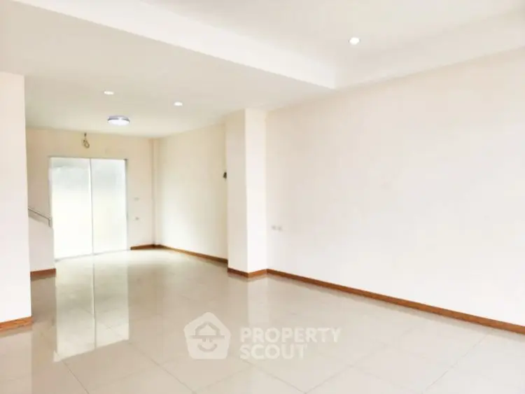Spacious empty room with glossy tiled floors and bright lighting, ideal for customization.