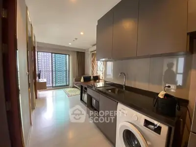 Modern apartment with open kitchen and living area, featuring a washing machine and large windows.