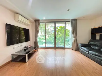 Spacious living room with large windows and modern furnishings in a serene setting.