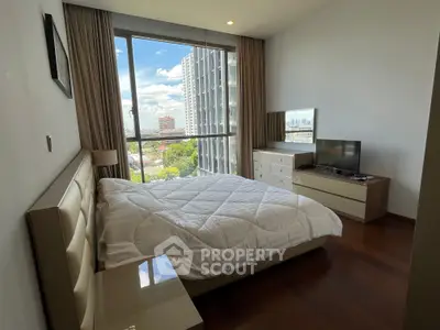 Spacious bedroom with large window offering stunning city views, modern furnishings, and ample natural light.