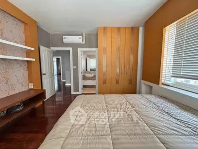 Spacious bedroom with modern decor and ample natural light, featuring built-in wardrobe and elegant wooden flooring.